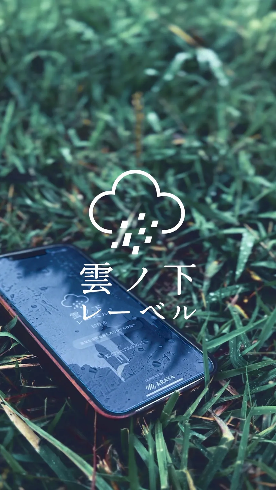 雨に濡れた芝生の上のスマートフォンに表示された雲ノ下レーベルのロゴ